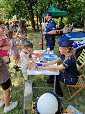 zdjęcie przedstawiające policjanta oraz dzieci i ich rodziców na pikniku z okazji Dnia Dziecka