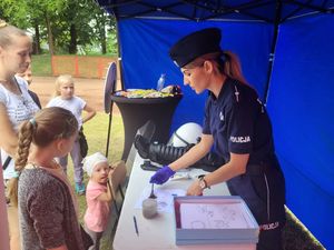 Policjantka robi pamiątkowe odbitki linii papilarnych dzieciom.