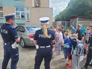 Policjanci ruchu drogowego prezentują dzieciom radiowóz.