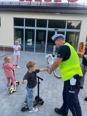 zdjęcie przedstawia policjanta wręczającego elementy odblaskowe