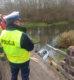 Policjant stoi na moście przy uszkodzonych barierach.