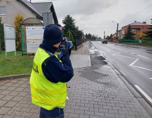 Policjantka mierzy prędkość poruszającego się auta.