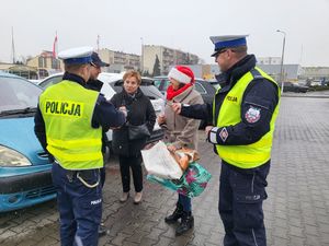 Policjanci wręczają przechodniom długopisy i elementy odblaskowe.