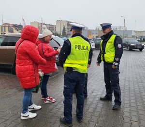 Policjanci wręczają przechodniom długopisy i elementy odblaskowe.