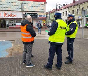 Policjanci wspólnie z przedstawicielem Przedsiębiorstwa Komunalnego na terenie miasta Wielunia rozdają opaski odblaskowe przechodniom.