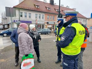 Policjanci wspólnie z przedstawicielem Przedsiębiorstwa Komunalnego na terenie miasta Wielunia rozdają opaski odblaskowe przechodniom.