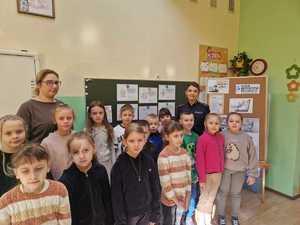 Policjantka z opiekunem  dziećmi w szkole pozuje do wspólnego zdjęcia.