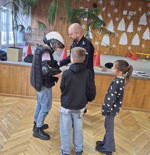 Policjant zakłada dziecku elementy umundurowania policyjnego.