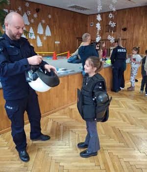 Policjant zakłada dziecku elementy umundurowania policyjnego.