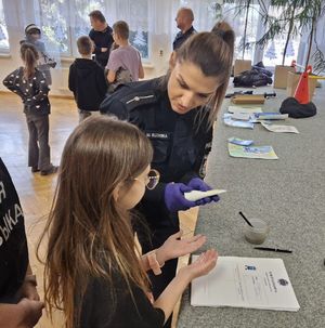 Policjantka robi dziecku pamiątkową odbitkę linii papilarnych.