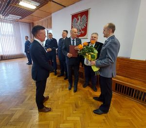 Wójtowie Gminy Biała, Czarnożyły, Skomlin wręczają kwiaty i podziękowania dla odchodzącego na emeryturę Komendanta Komisariatu Policji w Białej. W tle stoją komendanci policji.