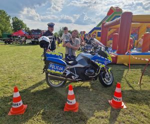 Dzieci pozują przy motocyklu policyjnym, obok stoją policjant i opiekun.