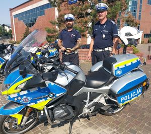 Policjanci stoją przy motocyklach policyjnych.