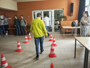Uczeń w założonych alkogoglach pokonuje tor przeszkód z pachołkami.