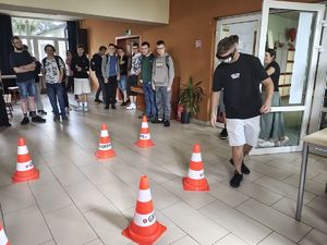 Uczeń w założonych alkogoglach pokonuje tor przeszkód z pachołkami.