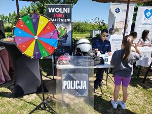 Policjantka na stoisku profilaktycznym robi pamiątkowe odbitki linii papilarnych.