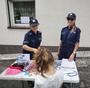 Policjantki na stoisku rozdają ulotki informacyjne.