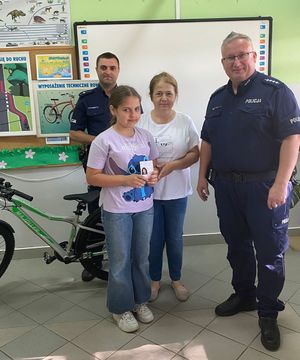 Policjant wręcza dziecku kartę rowerową.