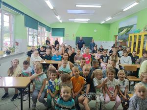 Dzielnicowy w sali w szkole wspólnie z nauczycielami i dziećmi.