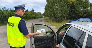 Policjant wręcza kierowcy ulotkę.