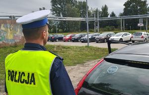 Policjant stoi przy aucie, z tyłu na szybie przyklejona naklejka akcji Mistrzu zwolnij.