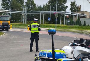 Policjant stoi na drodze nadzoruje na niej ruch.