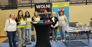 Policjantka, wraz z uczniami, nauczycielami ze Szkoły Podstawowej numer 4 w Wieluniu oraz przedstawicielem Gminnej Komisji Rozwiązywania Problemów Alkoholowych w Gminie Wieluń stoją stoisku profilaktycznym w hali WOSiR.