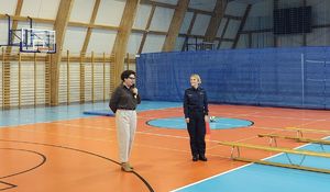 Hala sportowa. Wystąpienie Pani dyrektor Zespołu numer 1 w Wieluniu obok stoi policjantka.