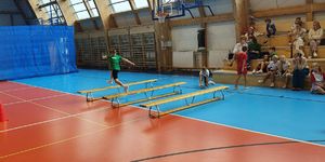 Hala sportowa. Dziewczynka przeskakuje przez ławki na torze przeszkód.