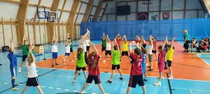 Hala sportowa. Dzieci rozstawione po hali wykonują ćwiczenia sportowe.