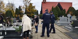 Policjanci idą przez cmentarz w Wieluniu.
