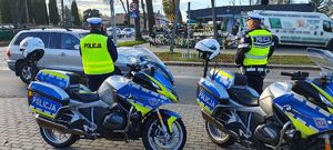 Dwa motocykle policyjne, przed nimi stoją dwaj policjanci.