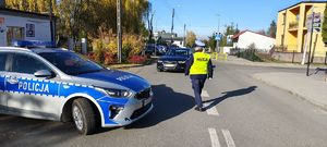 Radiowóz, policjantka idzie w kierunku nadjeżdżającego auta.