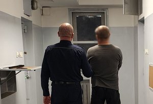 Policjant prowadzi zatrzymanego do celi.