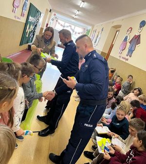Policjanci wręczają dzieciom dyplomy w szkole.