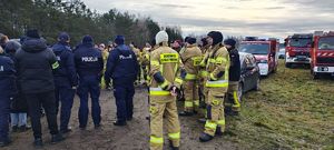 Policjanci i strażacy w miejscu koncentracji sił w miejscu gdzie będą prowadzone poszukiwania zaginionego.