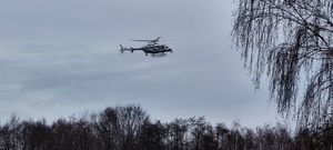 Śmigłowiec policyjny leci nad lasem.