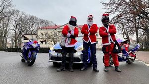 Trzej mężczyźni przebrani w stroje Mikołaja stoją przed radiowozem. Obok radiowozu stoją dwa motocykle.