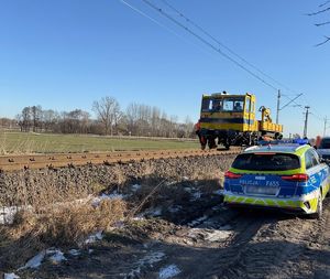 Tory na których stoi pojazd techniczny.  boku stoi radiowóz.