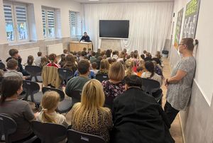 Policjant w sali prowadzi prelekcję z uczniami w klasie.