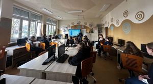 Policjantka prowadzi prelekcje w sali z uczniami którzy siedzą w ławkach.