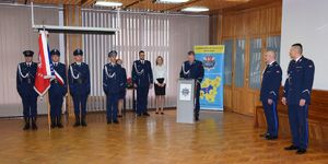 Zza mównicy przemawia młodszy inspektor Grzegorz Kurek, z boku stoi poczet sztandarowy oraz uczestnicy uroczystości.