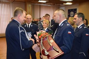 Młodszy inspektor Grzegorz Kurek odbiera gratulacje od funkcjonariuszy Komendy Powiatowej Policji w Wieluniu. Delegacja  wręczają mu szablę.