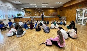 Policjantka prowadzi rozmowę z dziećmi w sali Wieluńskiego Spółdzielczego Domu Kultury.