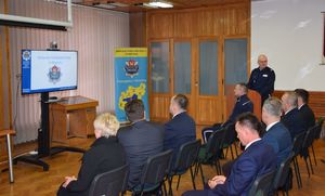 Uczestnicy  narady rocznej siedzą w sali odpraw, przy mównicy stoi Komendant Powiatowy Policji w Wieluniu.