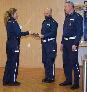 Zastępca Komendanta Wojewódzkiego Policji w Łodzi wręcza dwóm policjantów ruchu drogowego wyróżnienia.