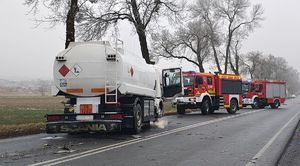 Cysterna biorąca udział w wypadku stoi na poboczu, na drodze porozrzucane elementy z pojazdu. Obok stoją dwa wozy strażackie.