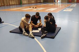 Uczniowie w grupach siedzą na materacach i rozwiązują test.