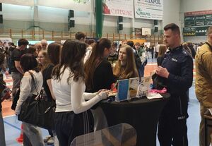 Hala Wieluńskiego Ośrodka Sportu i Rekreacji , uczestnicy targów edukacji przy stoisku rozmawiają z policjantami.