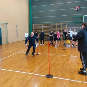 Hala sportowa w Szkole Podstawowej w Osjakowie, policjant biegnie po torze przeszkód, wokół stoi młodzież, która się przygląda.